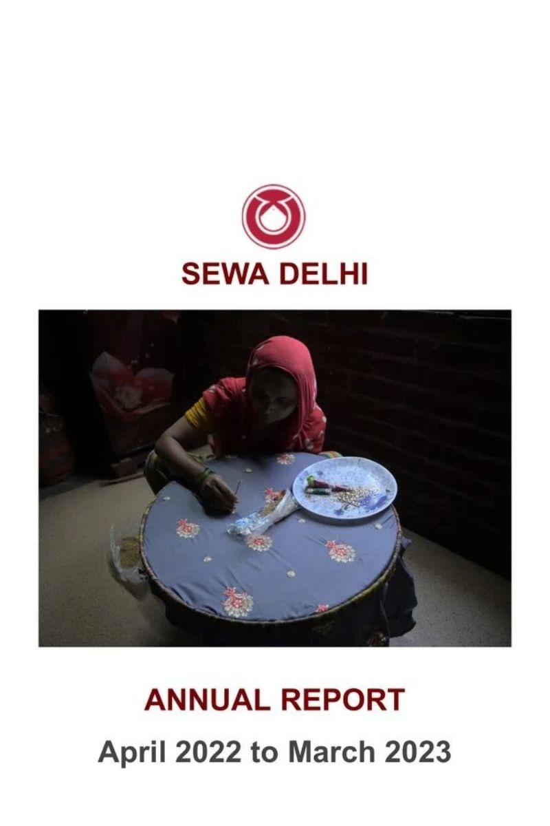 SEWA Delhi Annual Report April 2022 to March 2023 cover showing a home-based woman worker doing hand embroidery on a frame