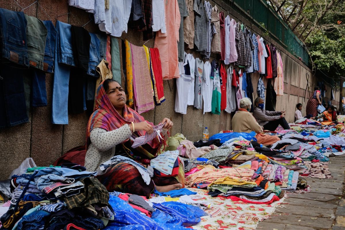 Woman street vendor arranging clothes for sale at a roadside market in Delhi.
